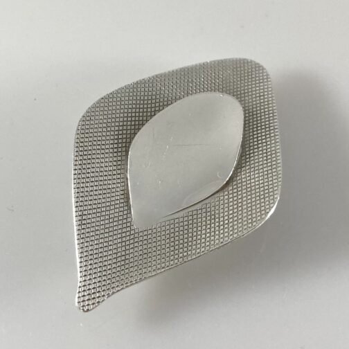 Silver brooch With Mirror by Grete Prytz Kittelsen; a well known design. Material stretches out as nature itself is drawn towards light.